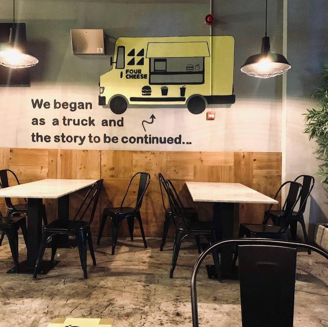 Four Cheese, Riyadh: a painted food-truck mural above timber wainscoting and metal chairs