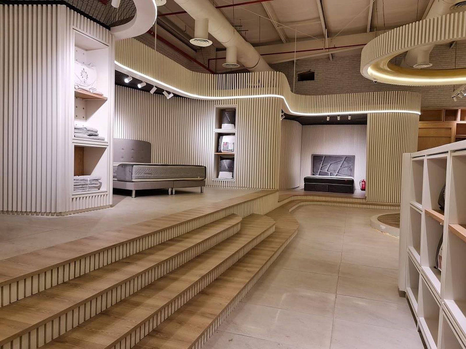Lyvva showroom, Buraida: stepped timber platforms and slatted display walls under cove lighting