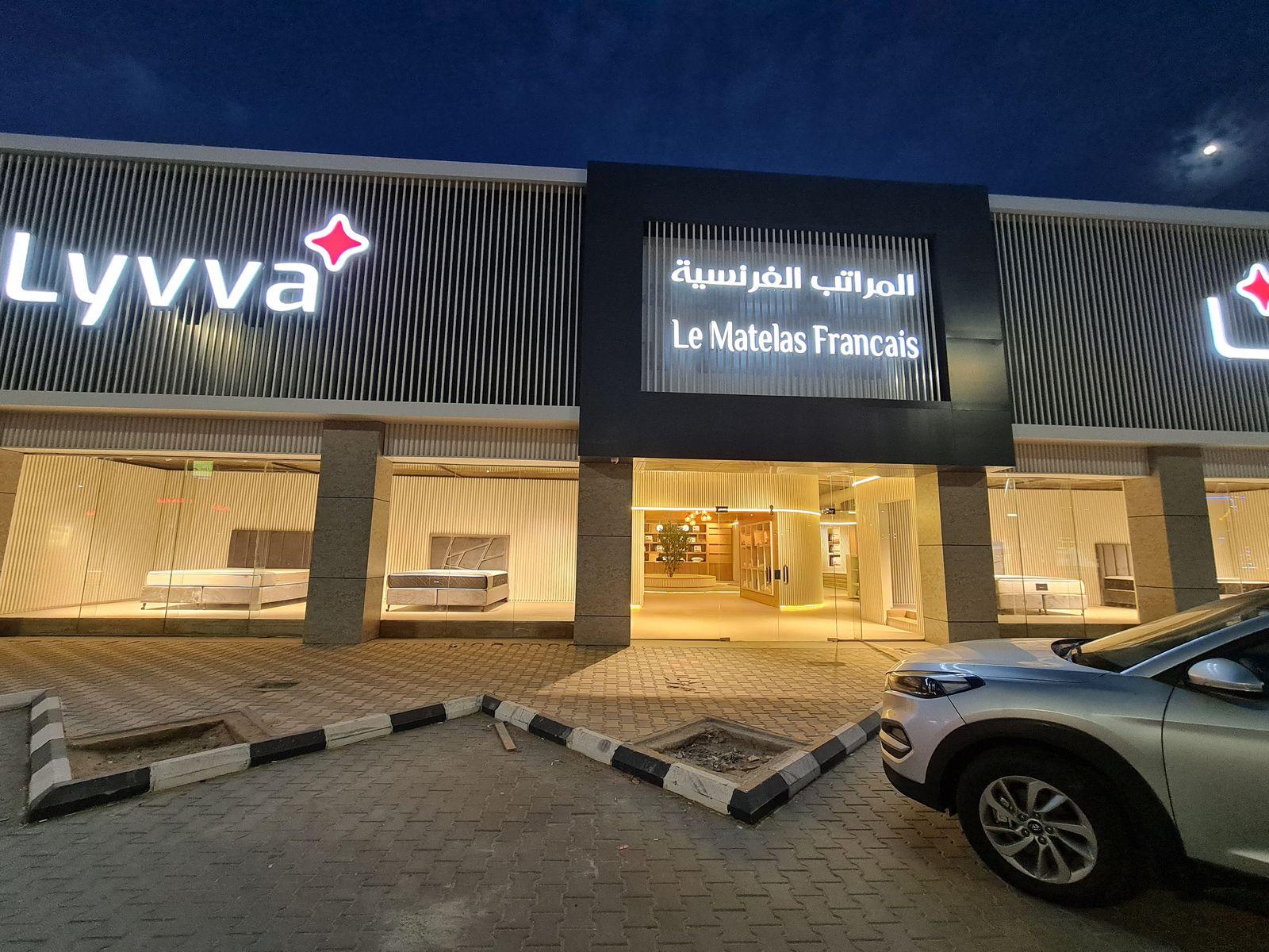 Lyvva showroom, Buraida, at night: the lit storefront and the brand signs above the glazing
