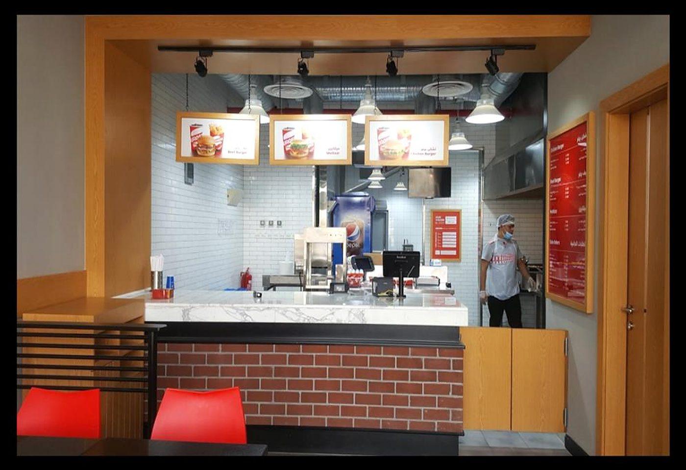 Burgerizzr, Riyadh: brick-clad counter, backlit menu boards and timber ceiling slats