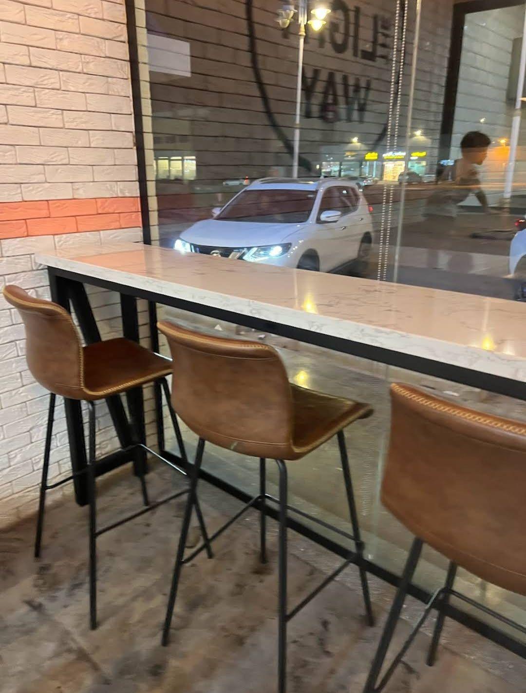The Light Way Burger, Riyadh: a window counter with leather bar stools