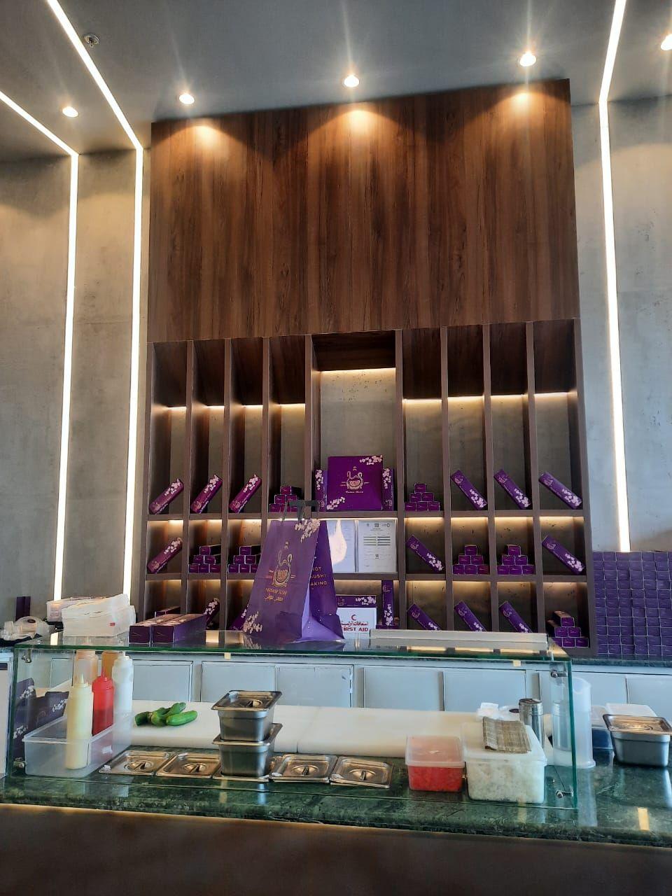 Masami Sushi, Riyadh: a full-height timber shelving wall behind the counter, edged in light